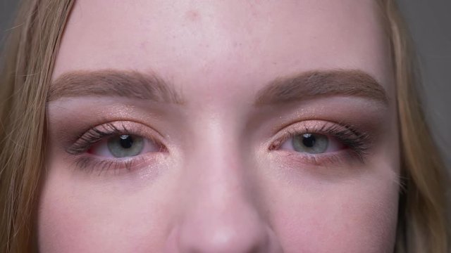 Closeup shoot of young attractive female face with eyes looking at camera being opened and closed in motion