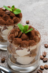 two portions Classic tiramisu dessert in a glass on concrete background