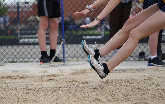 A Young Lady Lands In The Sand As She Competes In The Long Jump, During A High School Track Meet. 