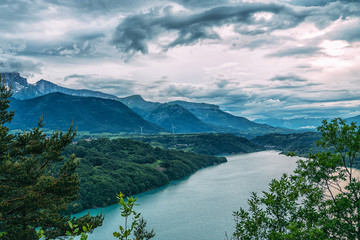 Amazing landscape of the Gorges Du Verdon in south-eastern France. Provence-Alpes-Cote d'Azur. Mountain canyon with dark water of Lake Sainte-Croix-du-Verdon. Dramatic cloudly sky and wooded shore.