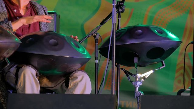 Man playing tank drum or hang on stage of ethnic open air concert. Relaxation, folk, meditative and traditional ethnic music concept