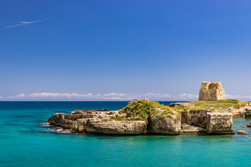 Fototapeta na wymiar The important archaeological site and tourist resort of Roca Vecchia, in Puglia, Salento, Italy. Turquoise sea, clear blue sky, rocks, sun, in summer. Messapic walls and ruins of the watch tower
