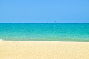 Fototapeta na wymiar Stripes of blue sky and green ocean and yelllow sand on beach
