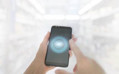 Shopping basket on a mobile phone screen. Woman Hand holding mobile phone on Supermarket blur background