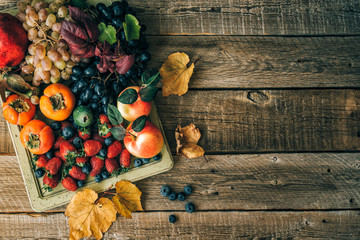 Rainbow fruits background. Strawberries, blueberries apples, grapes, persimmon, pomegranate on dark wooden table. Selective focus. Top view. Copy space.