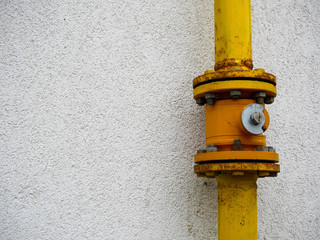Fototapeta na wymiar Yellow gas pipes connection on a residentual house wall close up shot, copy space.