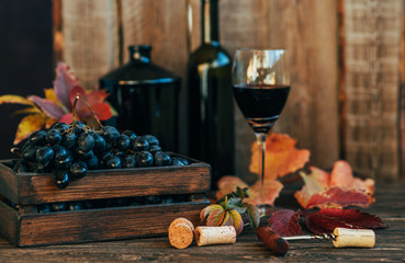 Excellent red wine bottles, wineglass and corkscrew on a rustic wooden table. Traditional...
