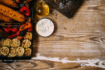 Summer or autumn food background. Ideas for barbecue and grill parties. Grilled corn, vegetables on a dark wooden table. Healthy food, organic, bio, homemade food. Copy space, top view.