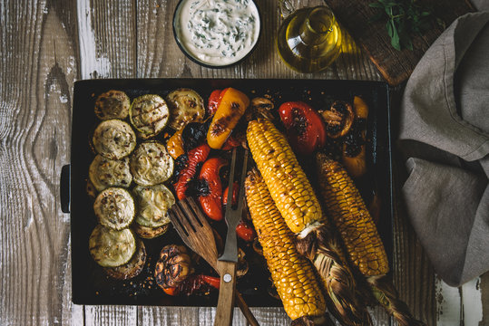 Corn grilled with vegetables and spices on the dark rustic background. Autumn food background. Toned image. Flat lay.