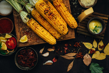 Grilled sweet corn with smoked paprika, dry tomatoes, salt and spices. Autumn vegan dinner or snack. Healthy food, organic, bio vegetables. Homemade food. Toned image. Flat lay with copy space.