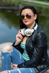 Brunette in sunglasses sits and listens to music in headphones