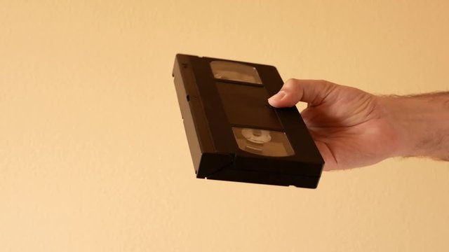 Man hand pulls out of the box a VHS video tape cassette
