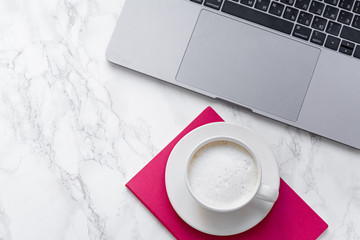 Flatlay with laptop, a cup of capuccino and copy space on marble background