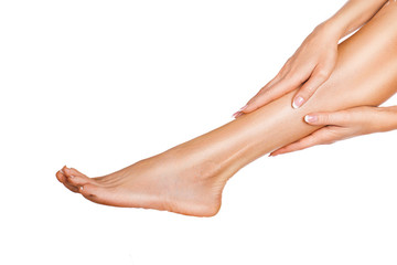 Woman massaging her legs isolated on white background. Close up view of a female legs with perfect skin and hands