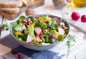 Fresh vegetable salad with radish, arugola, croutons on white wood