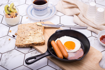 breakfast in pan with fried eggs, sausages, bacon, toasts and coffee
