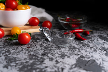 empty sauce cup or dish on a dark surface flat lay, different vegetables around, pepper, tomatoes b