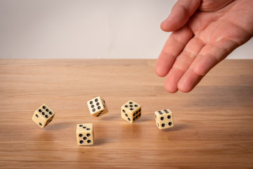 Hand throwing dice in front of a dark background.