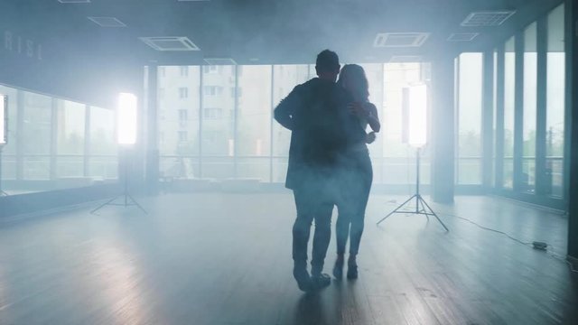 Professional dance studio and a young man and woman practicing. Partners performing kizomba dance moves.