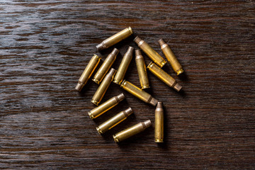 Empty bullet casings on a dark, wooden table.