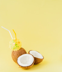 Fresh Coconut cocktail with a straws on yellow background, copy space
