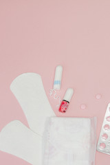 Sanitary pads and tampons and pills on pink background. Woman critical days, gynecological menstruation cycle. Menstruation sanitary woman hygiene. Medical concept.Top view, flat lay, copy space
