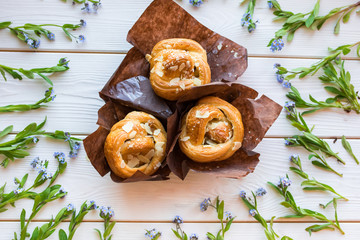 Fresh baked pastry with blue spring flowers on wooden table. Food, dessert concept. Sugar dessert with cream 