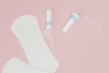 Women intimate hygiene products - sanitary pads and tampons on pink background, copy space. Menstrual period concept. Top view, flat lay, copy space