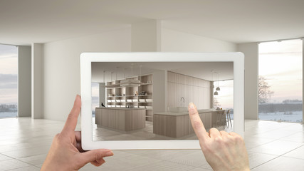 Augmented reality concept. Hand holding tablet with AR application used to simulate furniture and design products in empty interior with ceramic floor, modern white kitchen