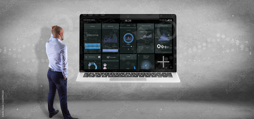 Poster businessman in front of a wall with laptop with business user interface data on the screen isolated 