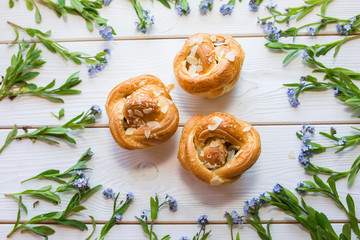 Fresh baked pastry with blue spring flowers on wooden table. Food, dessert concept. Sugar dessert with cream 