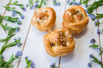 Fresh baked pastry with blue spring flowers on wooden table. Food, dessert concept. Sugar dessert with cream 