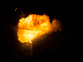 Realistic fiery explosion with sparks over a black background