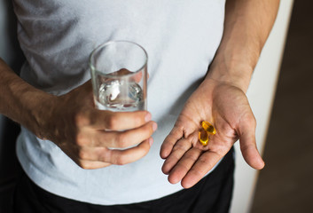  vitamins and a glass of water in the hands of a man