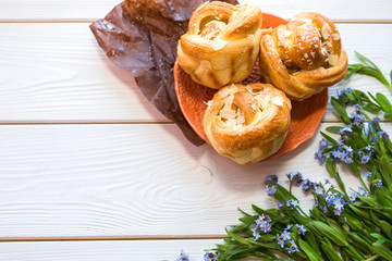 Fresh baked pastry with blue spring flowers on wooden table. Food, dessert concept. Sugar dessert with cream 