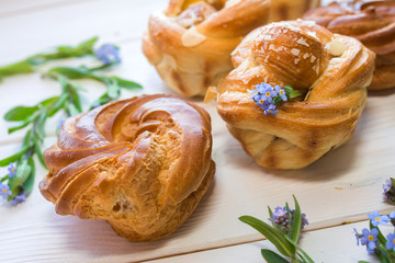 Fresh baked pastry with blue spring flowers on wooden table. Food, dessert concept. Sugar dessert with cream 