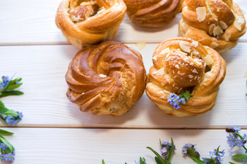 Fresh baked pastry with blue spring flowers on wooden table. Food, dessert concept. Sugar dessert with cream 