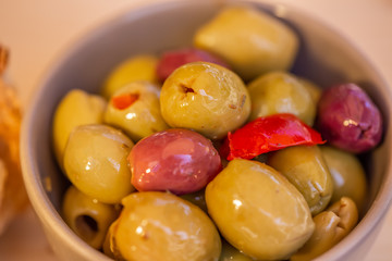 Olives stuffed, red pepper and spices of herbs. Multi-colored olives in a gray bowl on a rustic table. Blurry background. Macro. Soft focus. Top view.
