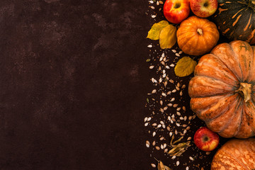 Autumn background with yellow leaves, red apples and pumpkins. Border of fall harvest on aged wood...