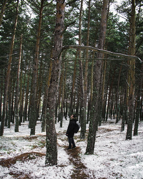 Man Traveler with backpack hiking in snow forest