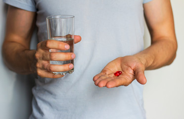  vitamins and a glass of water in the hands of a man
