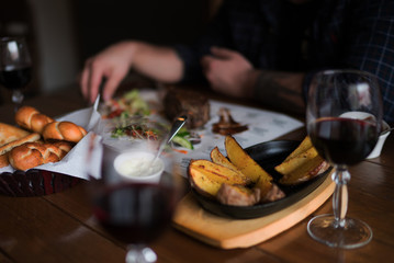 Eating and leisure concept. Dinner on the table. Tasty grilled lamb leg with vegetables and herbs on a roasting iron pan. Assorted delicious vegetables with grilled meat. Toned image. Selective focus