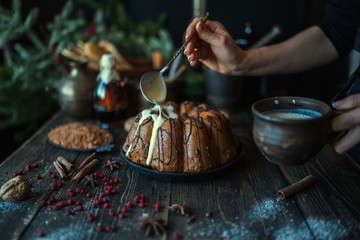 Holiday cake on wooden table with berry, spice and chocolate at rustic home kitchen. Christmas baking background. Ingredients for cooking on dark wooden background. Homemade festive food. Toned image