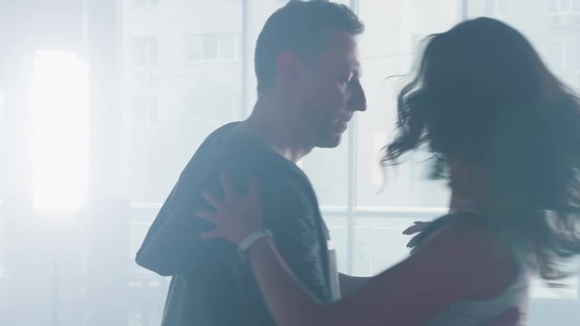 Performing a beautiful choreography in a dance studio. Kizomba or bachata dancers in dense smoke.