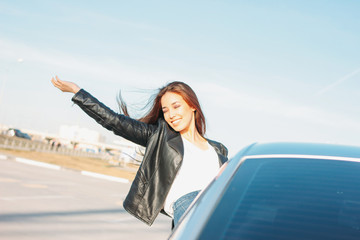 Happpy beautiful charming brunette long hair young asian woman in black leather jacket in car window at sunset