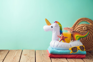 Summer vacation background with orange juice and unicorn pool float on wooden table © maglara
