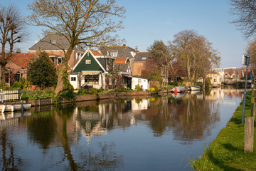 Fototapeta na wymiar View of wooden houses along a canal in the town Edam, Netherlands. Old Kwakel drawbridge in background