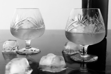 Glass of cognac with ice and ice spilled on the table