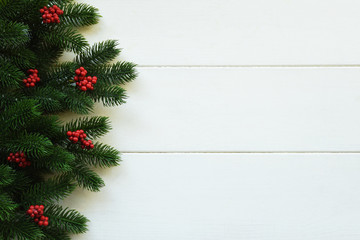 Christmas wooden background with fir branches and red berries. View with copy space.