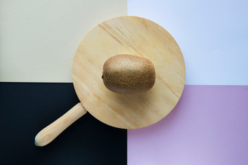 a kiwi on a cutting board on a background of four colors. the minimalist composition makes the...